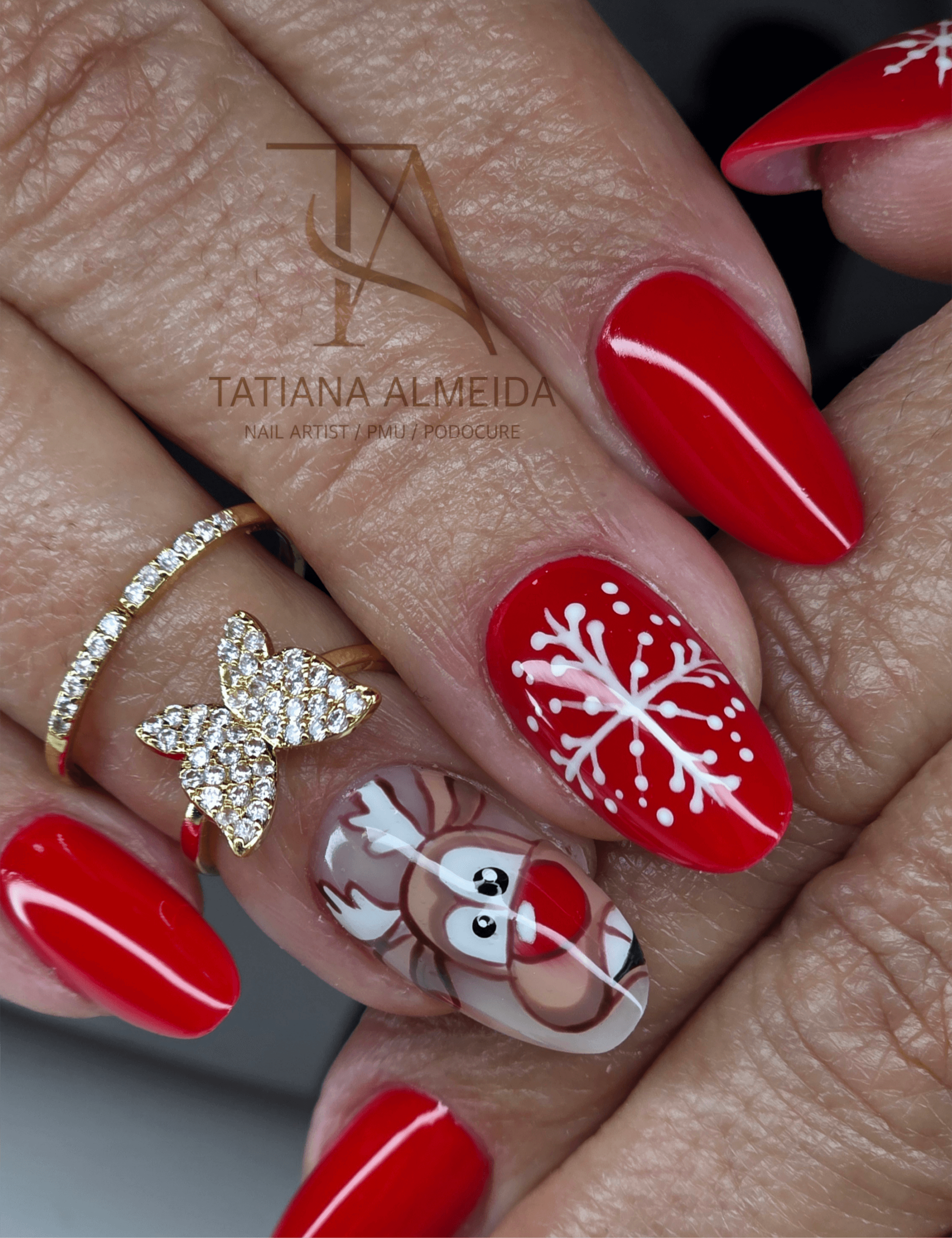 Manucure de Noël rouge avec un flocon de neige blanc et un renne dessiné.