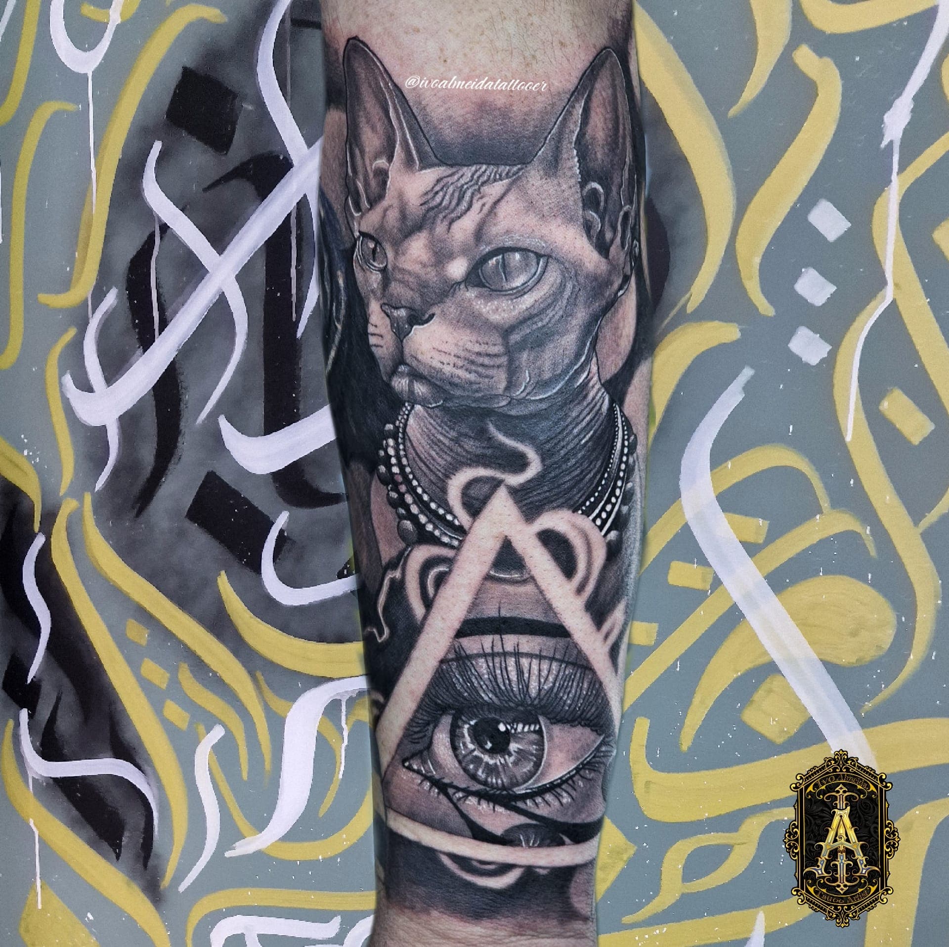 Tatouage d'un chat Sphynx et d'un œil dans un triangle sur un avant-bras.