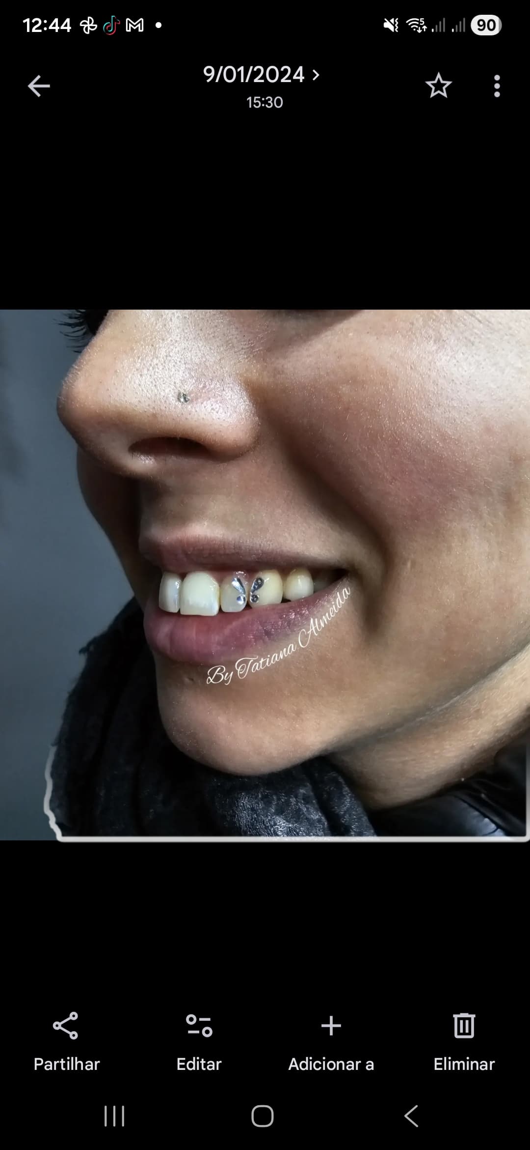Sourire d'une femme orné d'un bijou dentaire papillon et d'un petit piercing au nez.