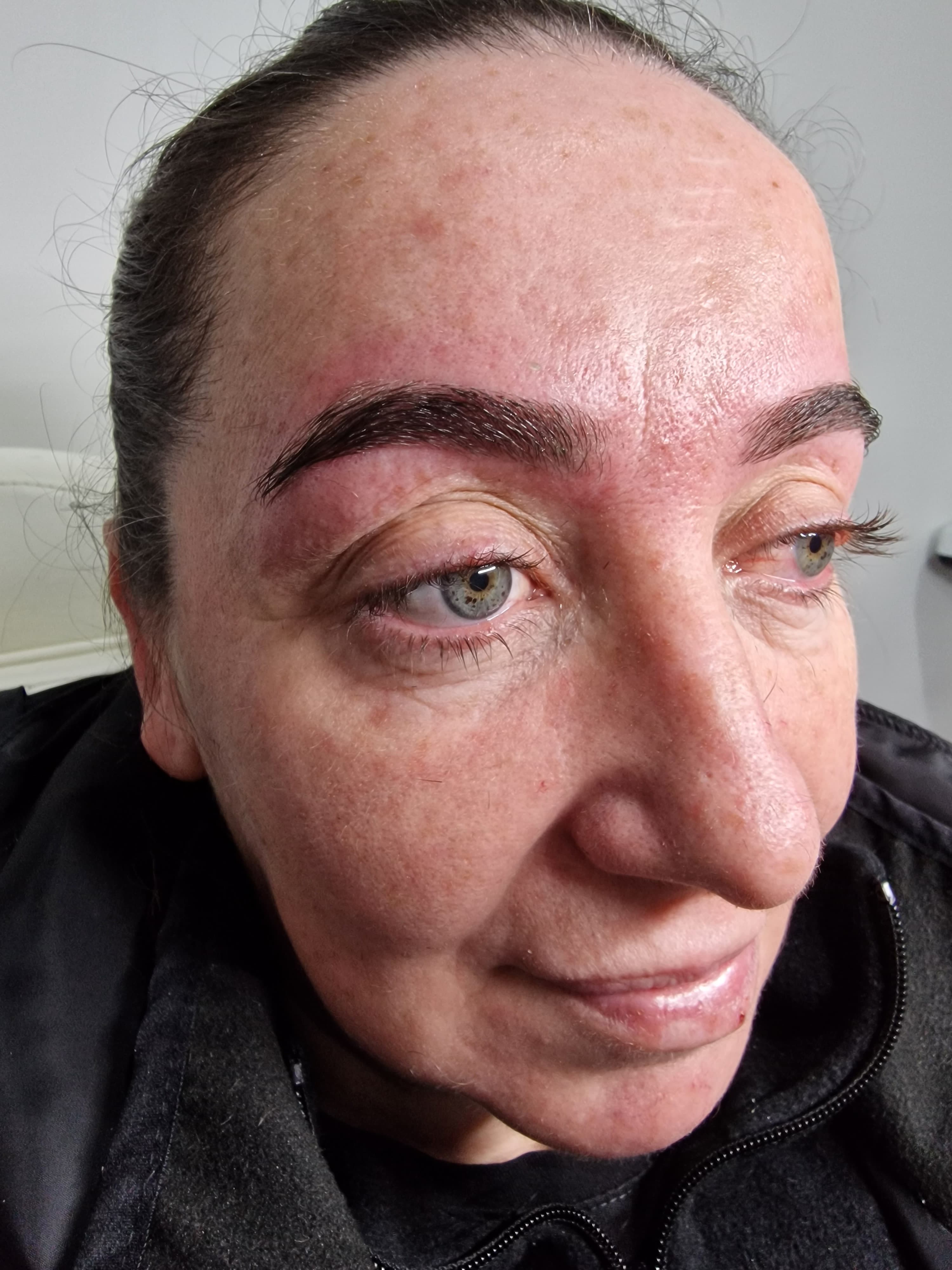 Gros plan d'un visage montrant des sourcils foncés fraîchement pigmentés et des yeux bleus clairs.